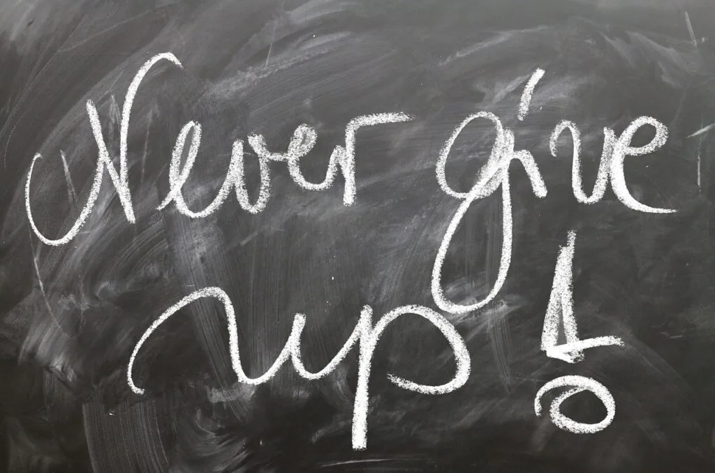 Napis kredą na czarnej tablicy: „Never give up!”